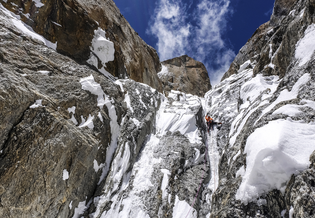 Marko Prezelj in the afternoon of the first day on the west face of Arjuna, climbing the first steep pitch of the route. At first the steeper ground was fun to climb--the sun was warm and the ice soft. In the afternoon the wall changed its mood. Several melodic avalanches of wet snow from above augmented their doubts. Prezelj noted that four or five times, after hearing a distant hiss, the blue sky above turned white, then black. Holding my tools tight sharpened my survival senses. Steepness was our patron. Most of the snow shipment went through the air. Doubts about the outcome were strong. [Photo] Urban Novak