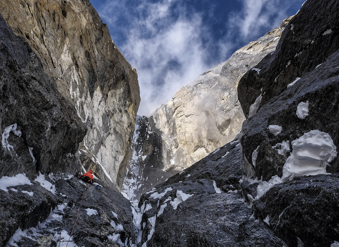 Prezelj on the fifth pitch on Day 1 of All or Nothing (ED+ M7+ WI5+ A0). The rock was wet from avalanches triggered by warm sun after several days of snowfall. The Slovenian team had a bivouac on the sloping ledge to the right. Above is the crux section. The main snow line in the gully was overhanging, so they climbed just to the right of it. [Photo] Urban Novak