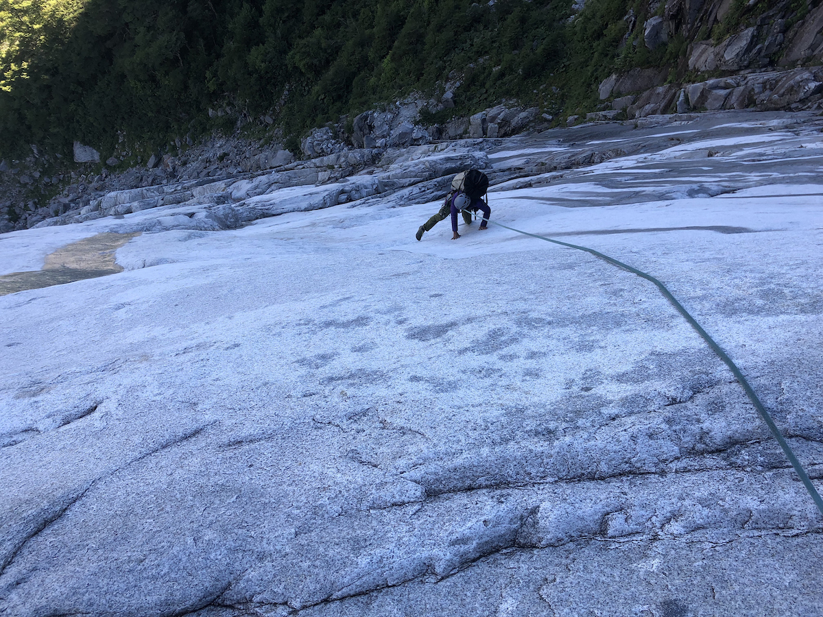 Neha Khurana following the opening slabs with a haul bag and portaledge on her back on an attempted new route in Cochamo with Kalman. Wet, vegetated, unprotectable rock eventually forced them to bail. [Photo] Chris Kalman