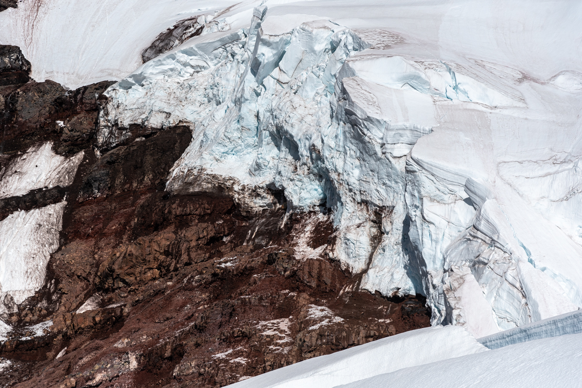 Climbers who choose to skirt the large crevasse at 8,800 feet on the Coleman-Deming route by going far left must pass directly along the base of this red cliff band with the serac overhead, where they are exposed to both rock- and icefall. [Photo] Matthew Tangeman