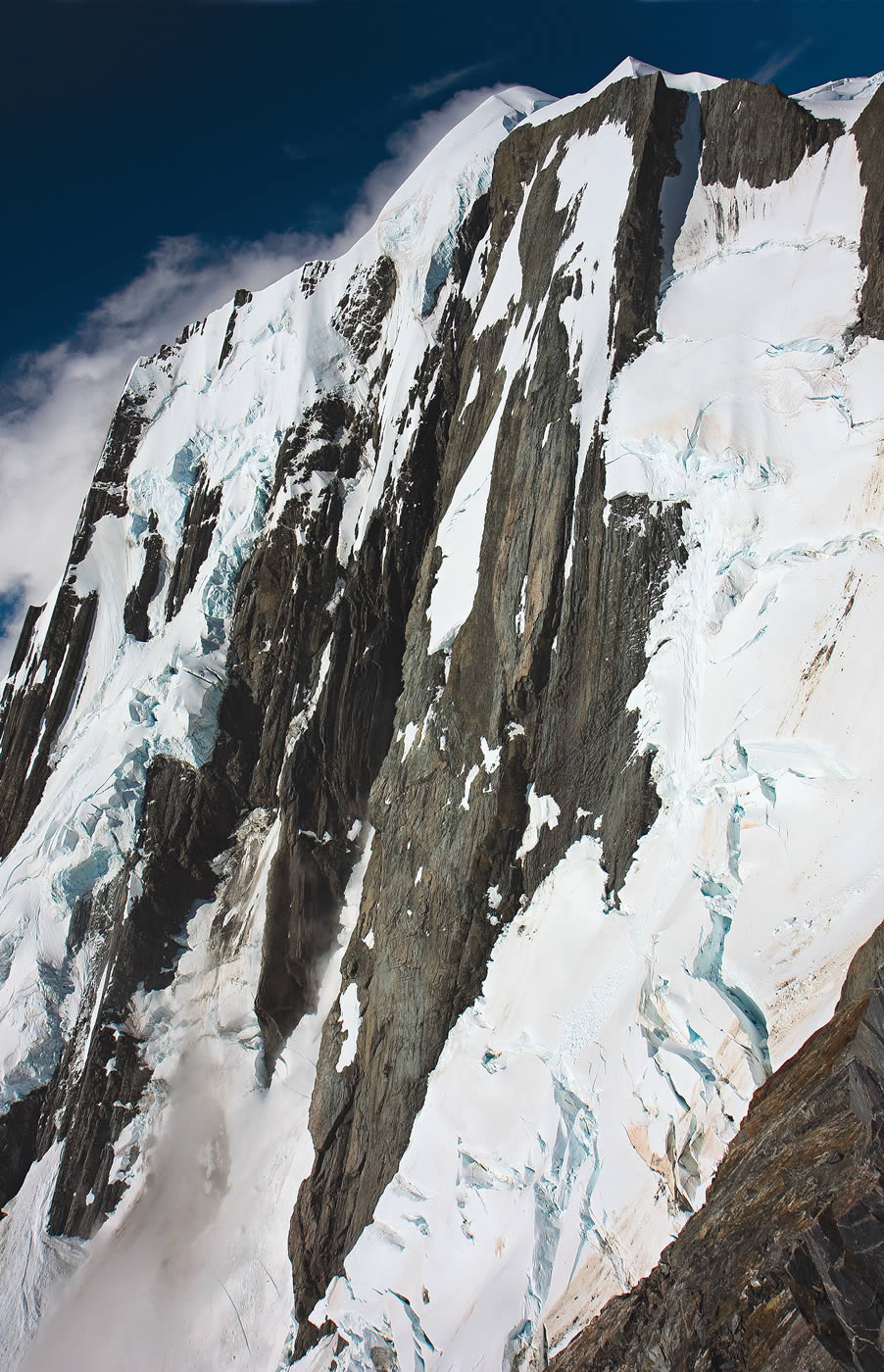 The Central Spur and Right Flank of the West (Spencer) Face of Elie de Beaumont, viewed from the West Rib of Mt. Walter. The left-hand dome is the summit. Rob Rainsbury and John Visser established the classic Central Spur in 1972. Kester Brown, editor of The Climber, the New Zealand Alpine Club magazine, says: Despite the elegance of the line... I'd be surprised if this route has had a single ascent in the last twenty years. Glacial recession vastly increased the difficulty of the multiday approach. [Photo] Kester Brown