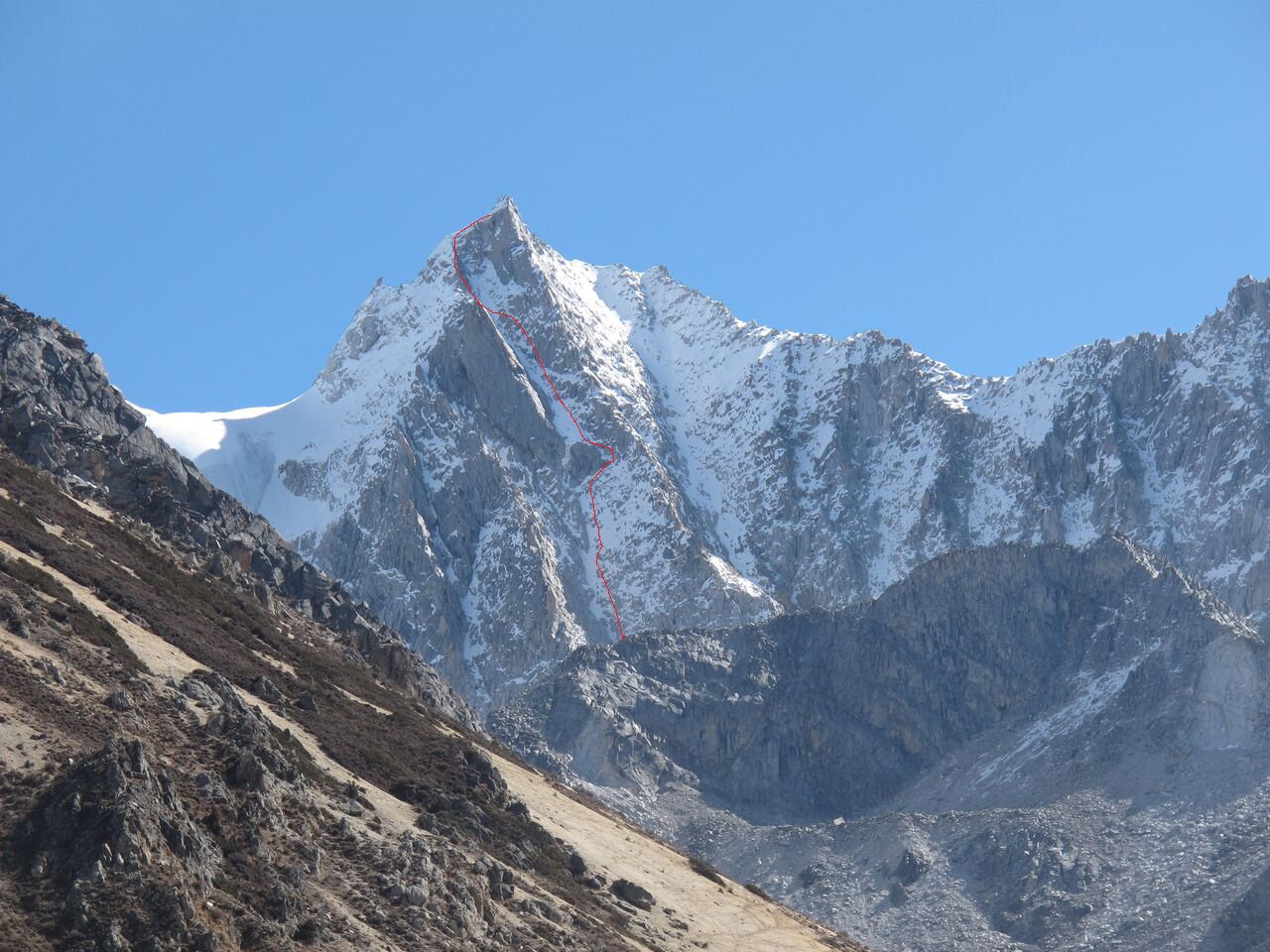 The red line shows the approximate route of Standing Room Only (Russian Alpine Grade 5a, Scottish IV, M4, 650m) on the West Face of Xialongrezha (5678m). The first four pitches are obscured below the fin of rock. [Photo] Rob Baker